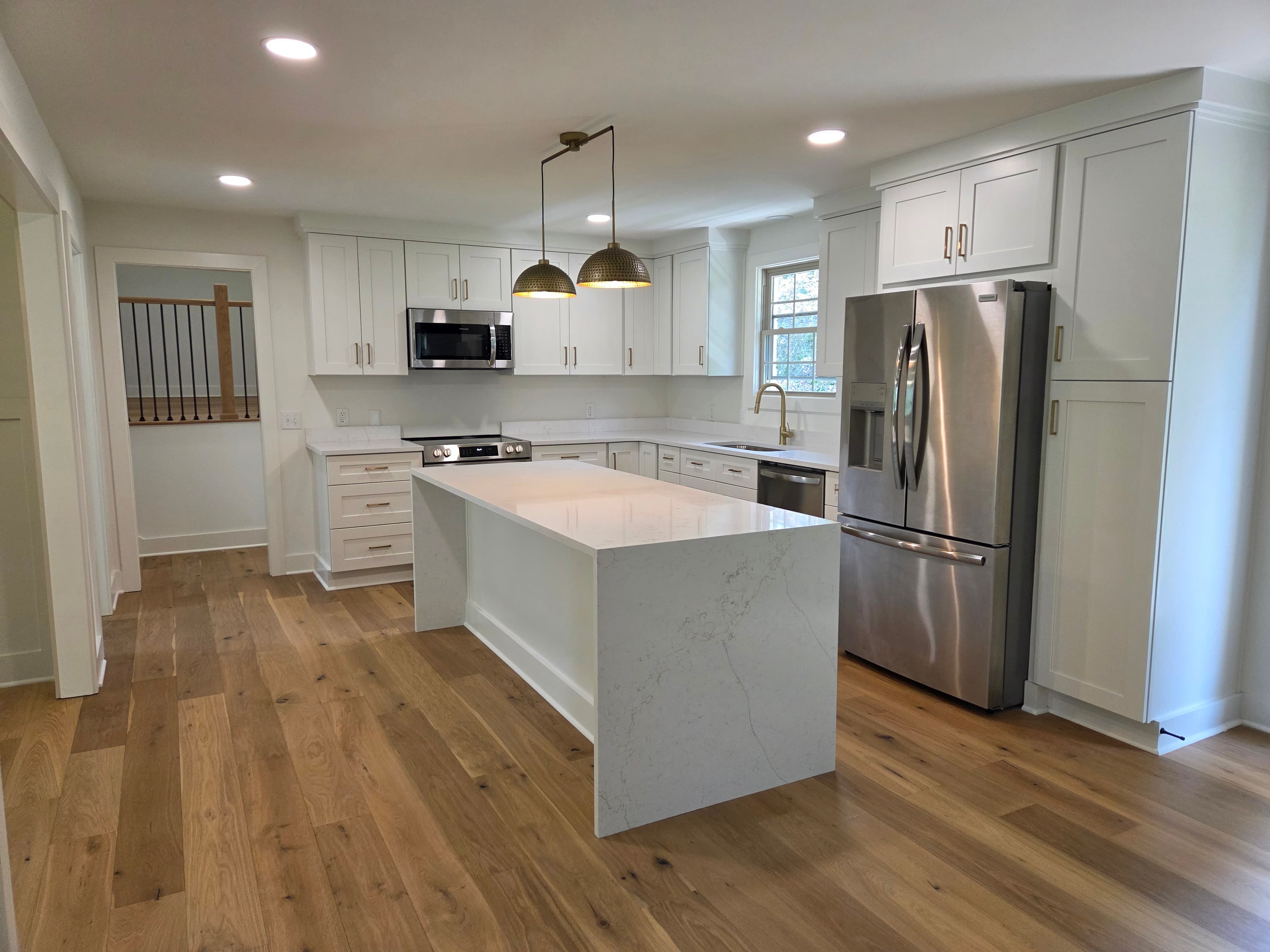 Whole kitchen renovation featuring a quartz waterfall island and hardwood floors
